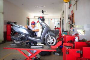 Mécanicien vérifiant un scooter sur un pont élévateur en atelier