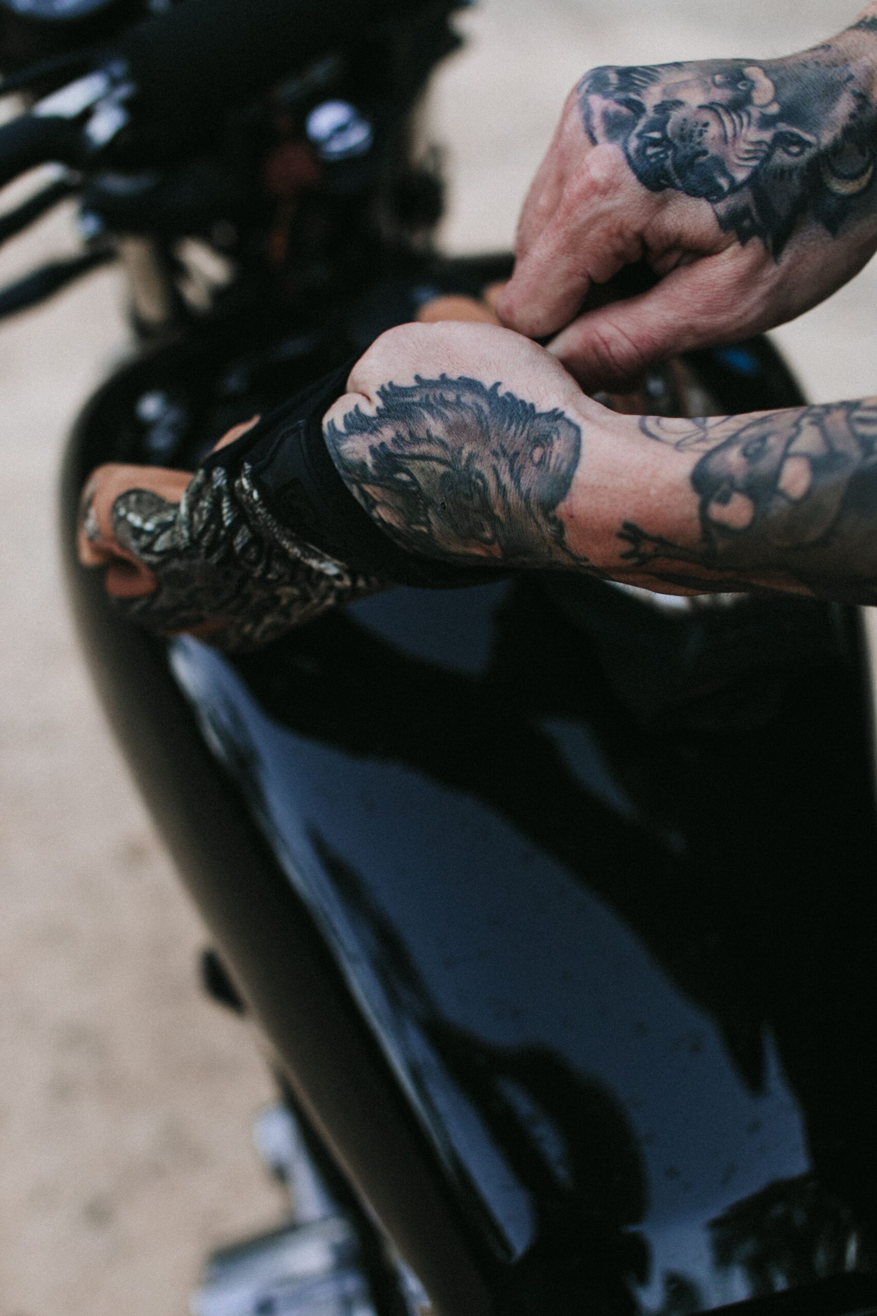 Motard tatoué enfilant des gants moto homologués
